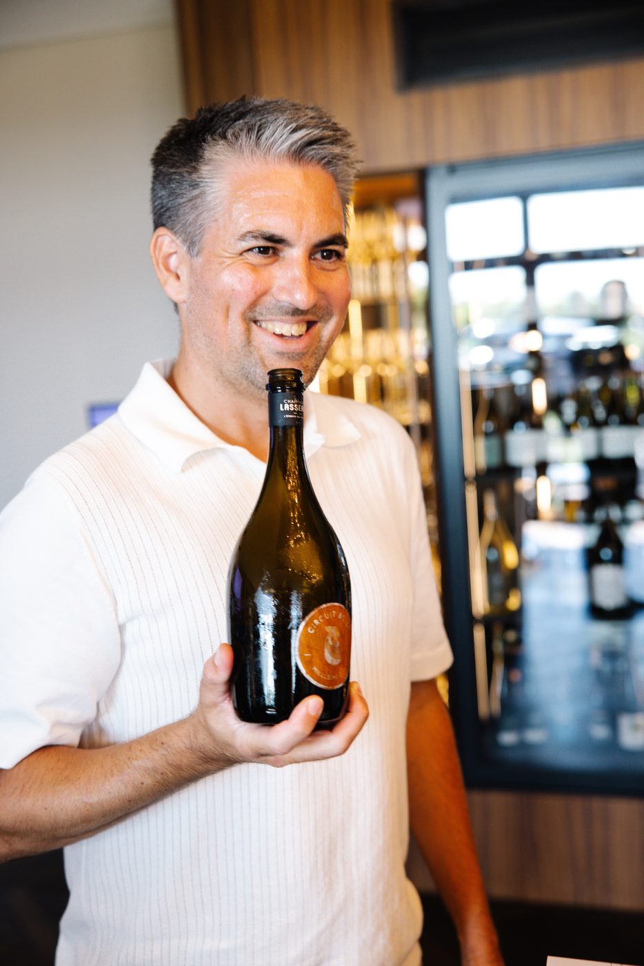 Marc führt lachend durch den Abend, Flasche in der Hand